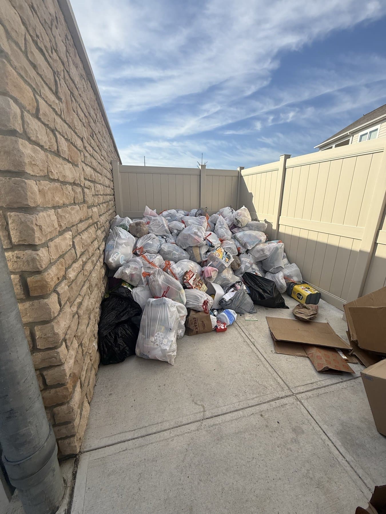Side yard filled with bags of trash and cardboard